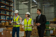 © visoot - Warehouse manager meeting with his team in a large distribution warehouse.