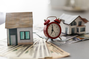 Dollar Banknotes For Buying House. House model and dollar banknote with alarm clock on white background