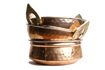 copper and stainless serving dishes (indian handi, karahi pots for food) cooking utensils made of hammered brass isolated on white background (spoon, bowl with handles) stacked