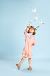 canvas print picture - Full-length portrait of playful, lovely little girl in pink dress posing, playing with paper birds against blue studio background. Concept of childhood, emotions, fun, fashion, lifestyle, imagination