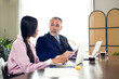 © NVB Stocker - woman secretary. Smiling Asian female secretary gives CEO senior business owner paper documents