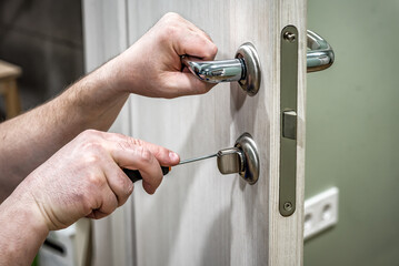 Wall Mural - Professional handyman repair the door lock in the room, locksmith fixing lock with screwdriver