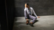 © NVB Stocker - Portrait man stressed sad and tired from over working. Overworked and worried. male business man worker sitting on the floor and dark background