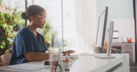 Wall Mural - Portrait of a Black Female Medical Health Care Professional Working on Desktop Computer in Hospital Office. Clinic Head Nurse is Appointing Prescriptions Online, Updating Electronic Health Records