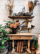 Rustic, weathered garden table with clay pots and assorted plants and ferns in a serene soft daylight