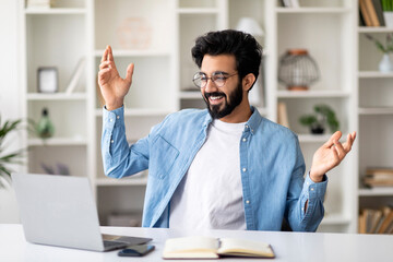 Wall Mural - Excited indian man celebrating business success with laptop at home office