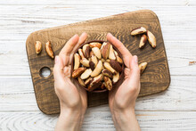 Woman Hands Holding A Wooden Bowl With Brazil Or Bertholletia Nuts. Healthy Food And Snack. Vegetarian Snacks Of Different Nuts