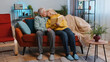 © Andrii Iemelianenko - Senior family grandparents man woman reading interesting book, talking and laughing at home. Elderly grandmother, grandfather couple enjoying leisure hobbies together sitting on sofa in living room