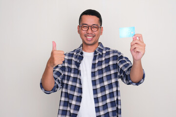 Wall Mural - Adult Asian man smiling happy and give thumb up while showing credit card