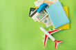 © Artsaba Family - Composition from a city map with a bank card, euro, dollar banknotes, passports and a toy plane on a green background. Travel and vacation concept.