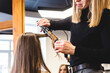 Master woman hairdresser gently curls hair curling girl in a beauty salon. Hair styling