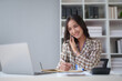 © amnaj - Happy beautiful smiling Asian businesswoman talking on mobile phone while working in office. Asian businesswoman making telephone call at office , enjoying talk, communication
