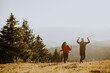 © BGStock72 - Smiling couple walking with backpacks over green hills