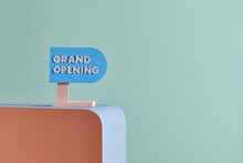 Grand Opening, Text Message On Blue Signboard On Color Table