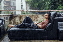 Man Lies On A Sofa Under Heavy Rain