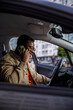 © Jovo Jovanovic/Stocksy - Young man talking on mobile phone while sitting in car