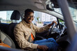 © Jovo Jovanovic/Stocksy - Portrait of happy man sitting in car holding steering wheel