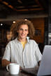 © Jovo Jovanovic/Stocksy - Happy male entrepreneur with laptop and coffee cup at cafe