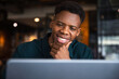 © Jovo Jovanovic/Stocksy - Smiling man using laptop with his hand on chin