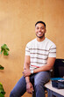 © ALTO IMAGES/Stocksy - Happy African American man sitting on table in office