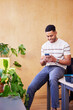 © ALTO IMAGES/Stocksy - Positive black man with smartphone during break in office