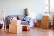 © ALTO IMAGES/Stocksy - Stack of cardboard boxes with belongings on wooden floor near sofa