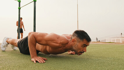 Middle aged muscular man doing push up exercises outdoors