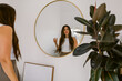 © ByLorena/Stocksy - Woman reflected in circular mirror at home