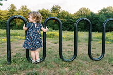 Smiling, Happy Toddler Girl Standing On A Bike Rack