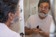 © Jordana Sheara/Stocksy - Man shaving his beard at home