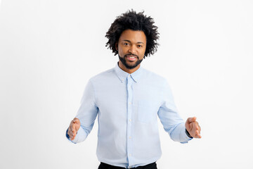 Smiling Aferican-American young man holding two hands in front of him and shows the wide size, curly guy in white shirt advertising novelty, presenting some product isolated on white background