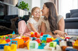 © dtatiana - Little girl play with constructor toy on floor in home with mom or woman babysitter, educational game, family at home spend leisure activities time together concept
