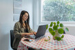 © Daniel Gonzalez/Stocksy - Smiling woman using laptop at home