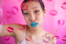 Woman With Colorful Makeup Behind Wall With Kiss Stains