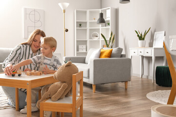 Poster - Mother and her little son playing with wooden toys at home