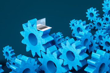 Laptop computer next to cogwheel gears