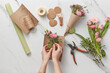 © Yaroslav Danylchenko/Stocksy - Female florist putting spring flowers in paper.