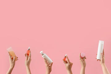 Hands holding cosmetic products on pink background