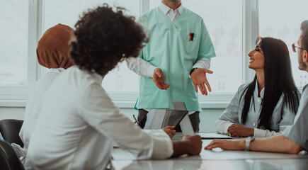 A group of multiethnic medical professionals including doctors, surgeons, and nurses are gathered in a hospital setting discussing patient care and using modern technology to address challenges in