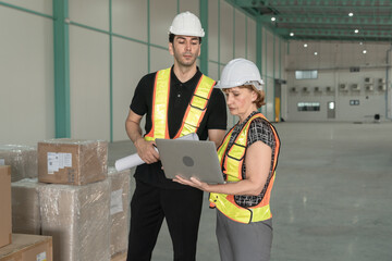 Industrial engineers men and women wearing safety helmets and reflective cloth.Use laptop and drawing projects to check products.Working in heavy industry production facility.