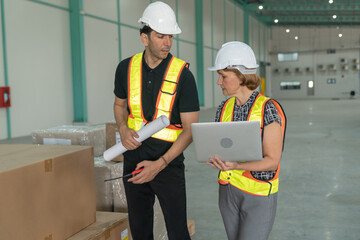 Industrial engineers men and women wearing safety helmets and reflective cloth.Use laptop and drawing projects to check products.Working in heavy industry production facility.