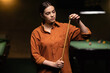 © mtrlin - Beautiful woman billiard player, Snooker, chalking the cue in motion standing near green tables.
