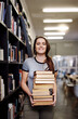 Woman, student with stack of books in library and research for project, studying and learn on university campus. Young female person smile in portrait, education and scholarship with course material
