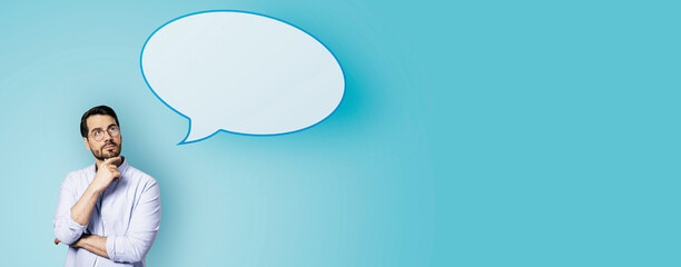 Aufkleber - Attractive young european businessman with speech bubble on wide blue background. Opinion, speech and communication concept. Mock up place.