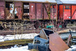 Alte abgewrackte rostende Güterwaggons auf einem Abstellgleis mit vorgelagertem Schrott im Winter.