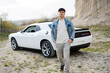 © AS Photo Family - Handsome man in jeans jacket and cap walking near his white muscle car in career.
