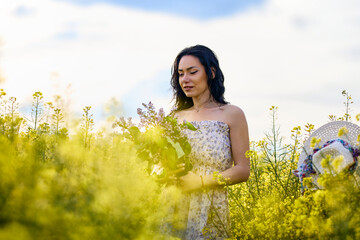 Wall Mural - portrait of a brunette woman in a rapeseed field in spring