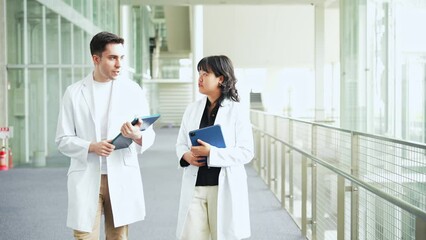 Poster - Multinational group walking in the lobby wearing white coats.