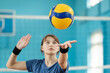 Photo in action of a young girl serving the ball. Learner practicing fundamental volleyball skill, serving the ball to opponents side