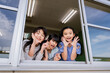 学校の教室の窓から運動場の生徒を応援する小学生の女の子